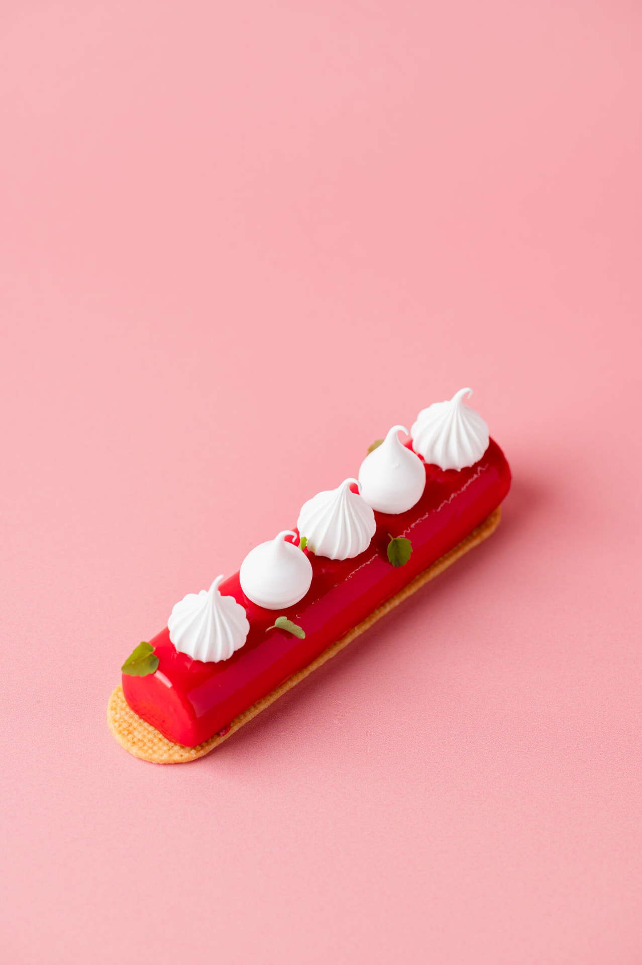 Langwerpig gebakje met rode glazuur en meringue